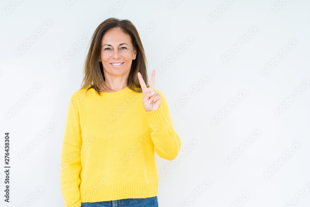 Beautiful middle age woman wearing yellow sweater over isolated background showing and pointing up with fingers number two while smiling confident and happy. Beautiful middle age woman wearing yellow sweater over isolated background showing and pointing up with fingers number two while smiling confident and happy.