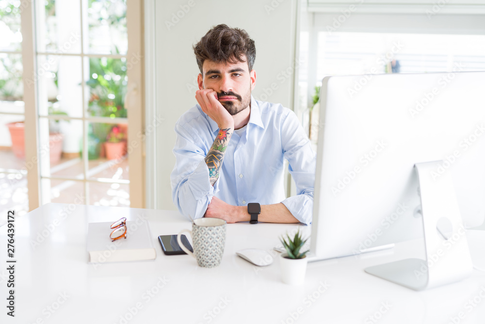 Young business man working using computer thinking looking tired and bored with depression problems with crossed arms.