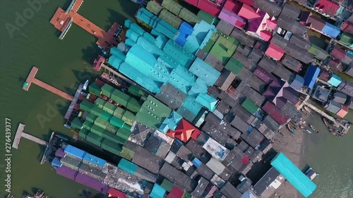 An aerial shot of the colorful roofs of houses and a big mosque in a settlement surrounded by water in Thailand