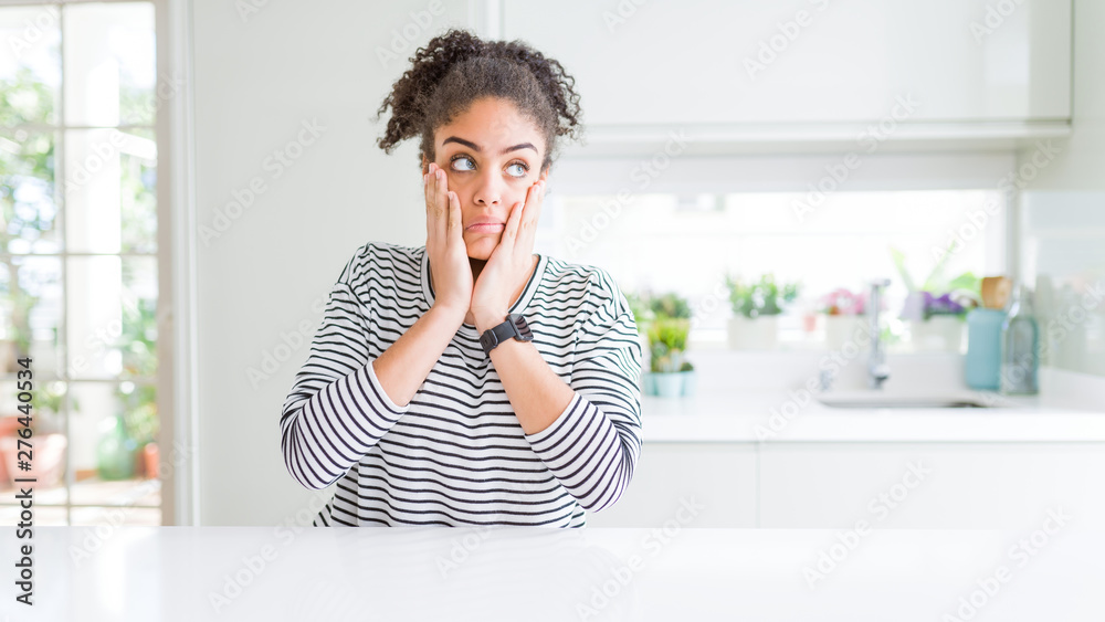 Beautiful african american woman with afro hair wearing casual striped sweater Tired hands covering face, depression and sadness, upset and irritated for problem