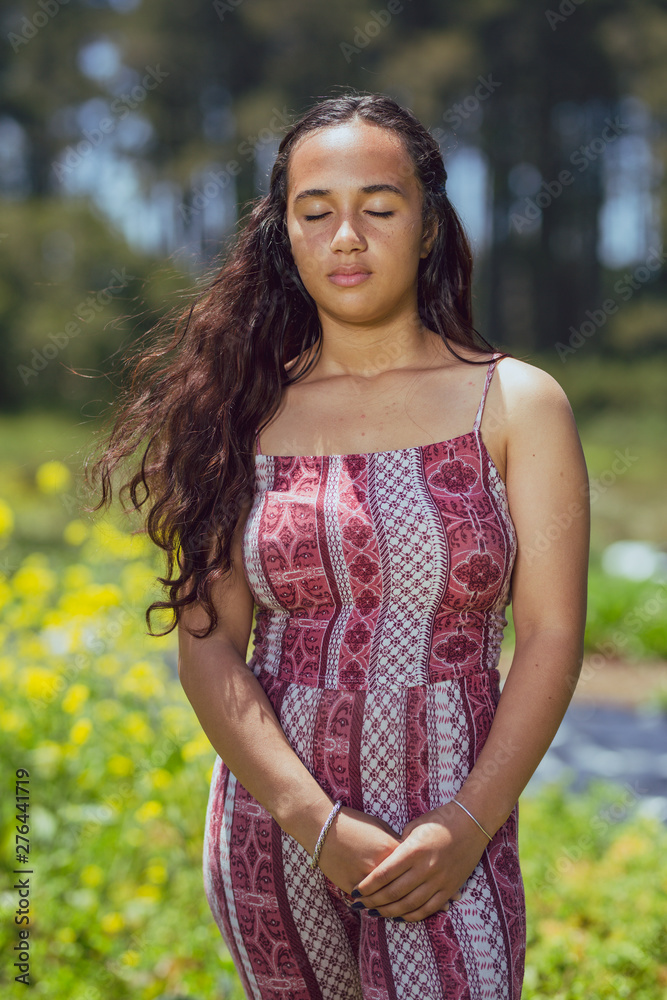Fototapeta premium Mixed race young woman stands in a flower field on a farm
