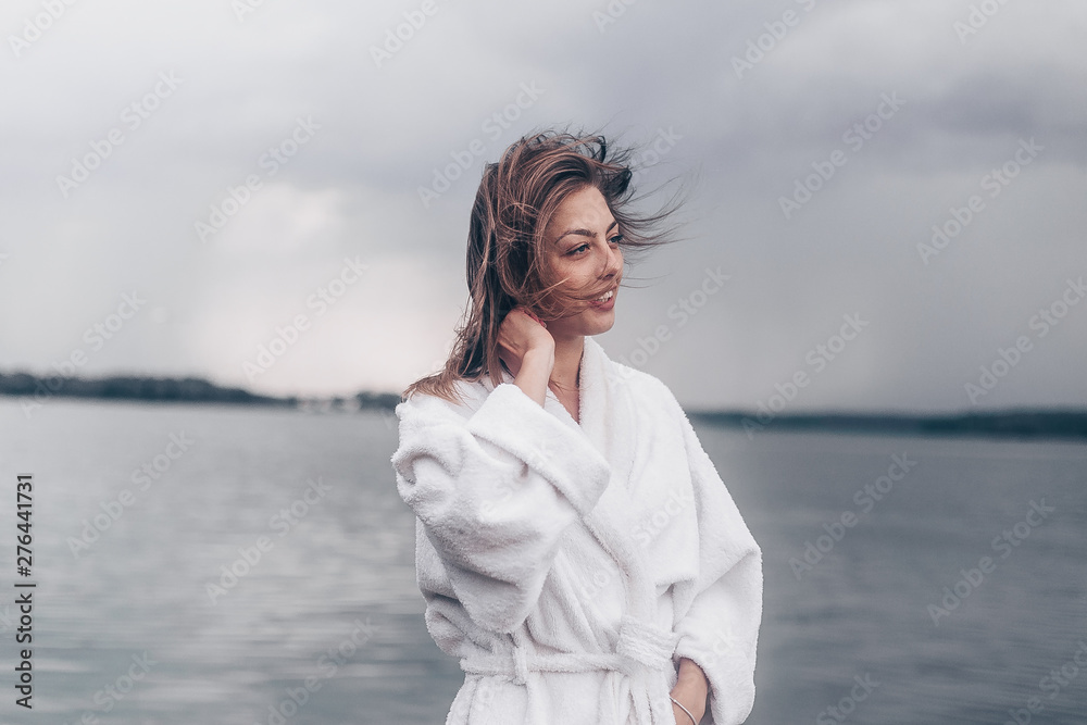 a girl in a white coat on the waterfront by the water.cloudy weather a girl in a white coat on the waterfront by the water.cloudy weather