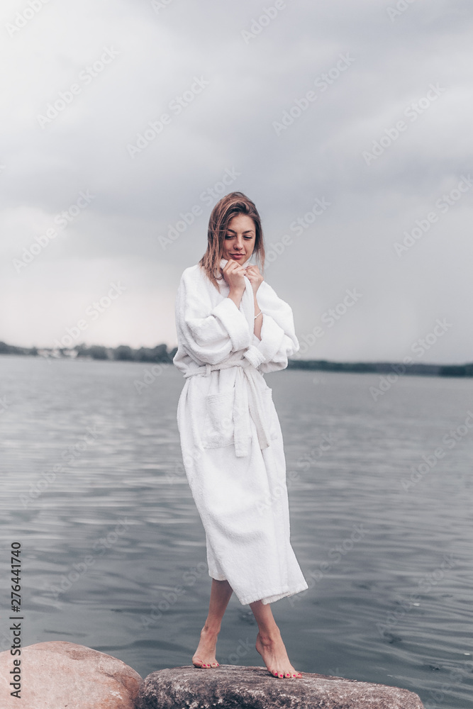 a girl in a white coat on the waterfront by the water.cloudy weather a girl in a white coat on the waterfront by the water.cloudy weather