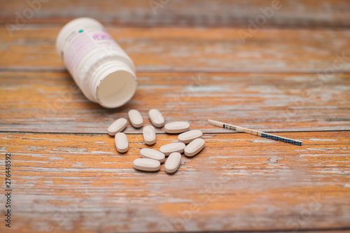 maternal and child health care. gray capsules with multivitamins for pregnant women and pregnancy test on wooden table.