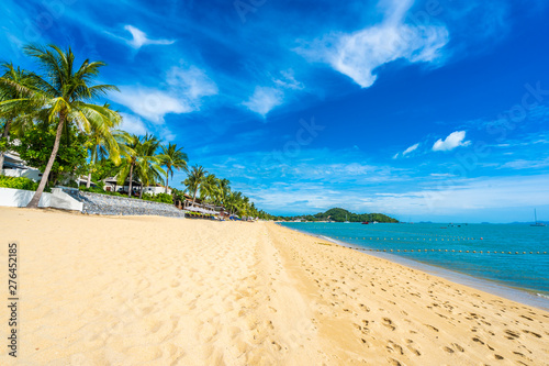 Fototapeta Naklejka Na Ścianę i Meble -  Beautiful tropical beach sea and ocean with coconut palm tree  and umbrella and chair on blue sky and white cloud