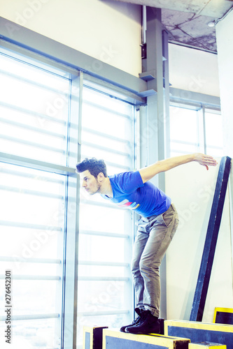 young handsome man doing parkour in gym inside, lifestyle sport people concept