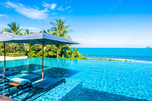 Beautiful luxury outdoor swimming pool in hotel resort with sea ocean around coconut palm tree and white cloud on blue sky