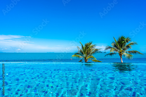 Fototapeta Naklejka Na Ścianę i Meble -  Beautiful luxury outdoor swimming pool in hotel resort with sea ocean around coconut palm tree and white cloud on blue sky