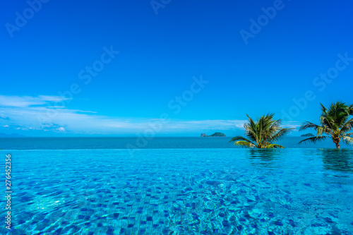 Beautiful luxury outdoor swimming pool in hotel resort with sea ocean around coconut palm tree and white cloud on blue sky