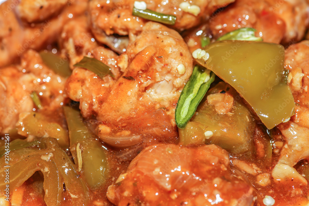 Chilli chicken - Spicy Indian food prepared with chicken in gravy sauce served with green chilli in macro view Chilli chicken - Spicy Indian food prepared with chicken in gravy sauce served with green chilli in macro view