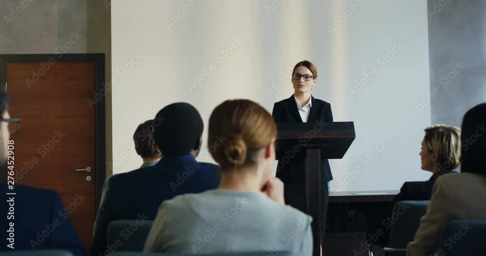 Caucasian man from the audience rising his hand up while wants to ask a question to the female professor at the podium. Back view. Caucasian man from the audience rising his hand up while wants to ask a question to the female professor at the podium. Back view.