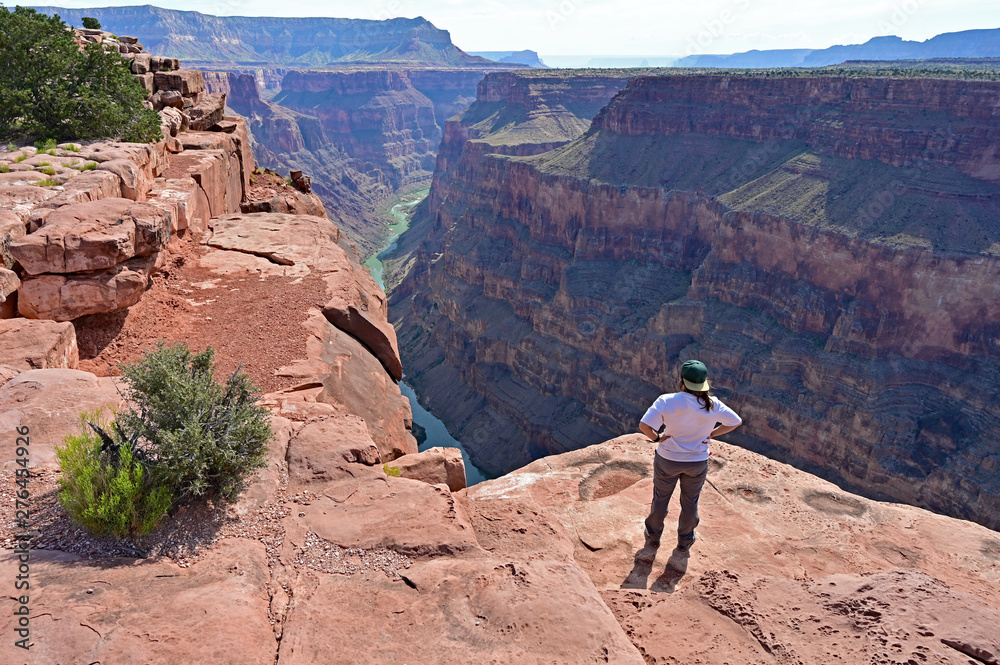 Young woman enjoys the spectacular view from Toroweap Overlook in Grand Canyon National Park, Arizona.