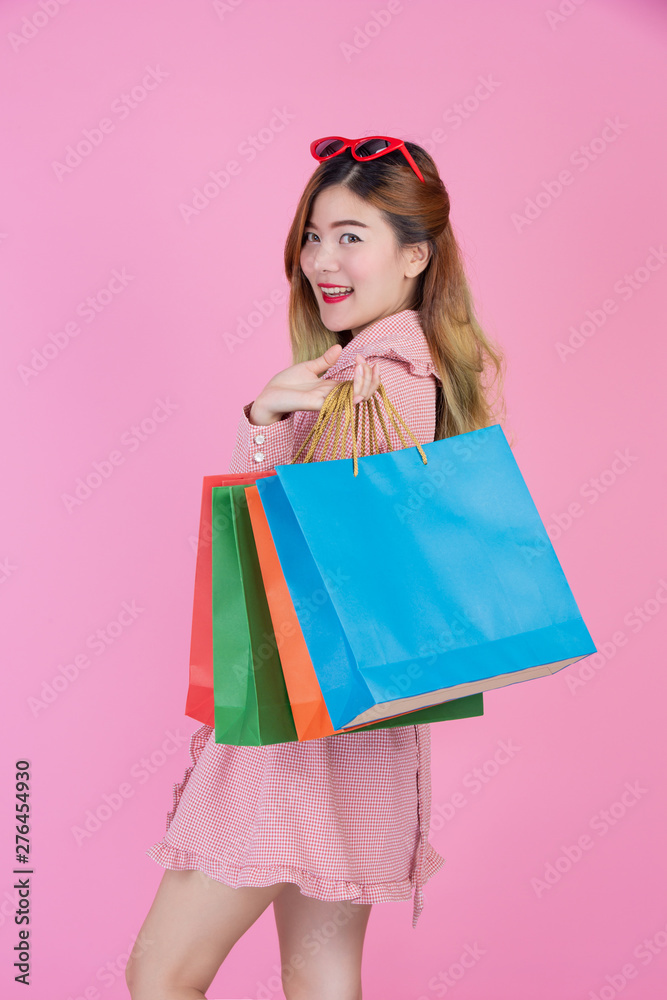 The girl holds a fashion shopping bag and beauty on a pink background.