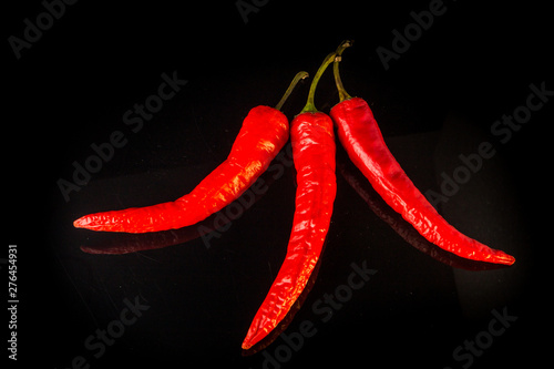 top view on three hot red chili peppers with reflection