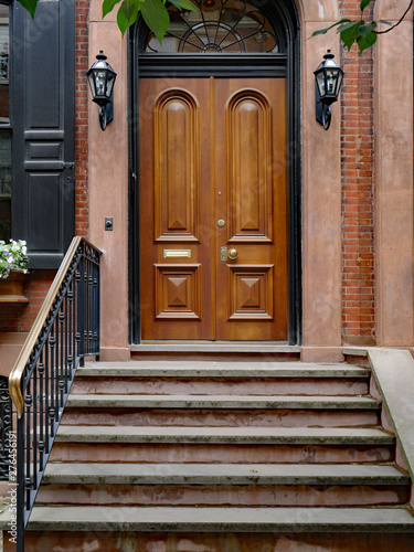 stone front step of elegant old urban brownstone type townhouse with polished double wooden door photo