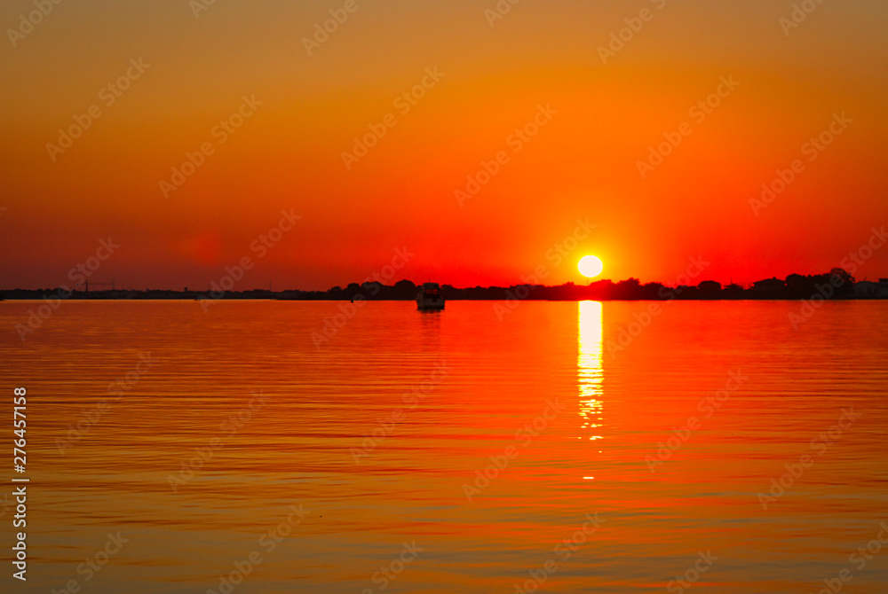Atardecer naranja y el sol se refleja en el agua