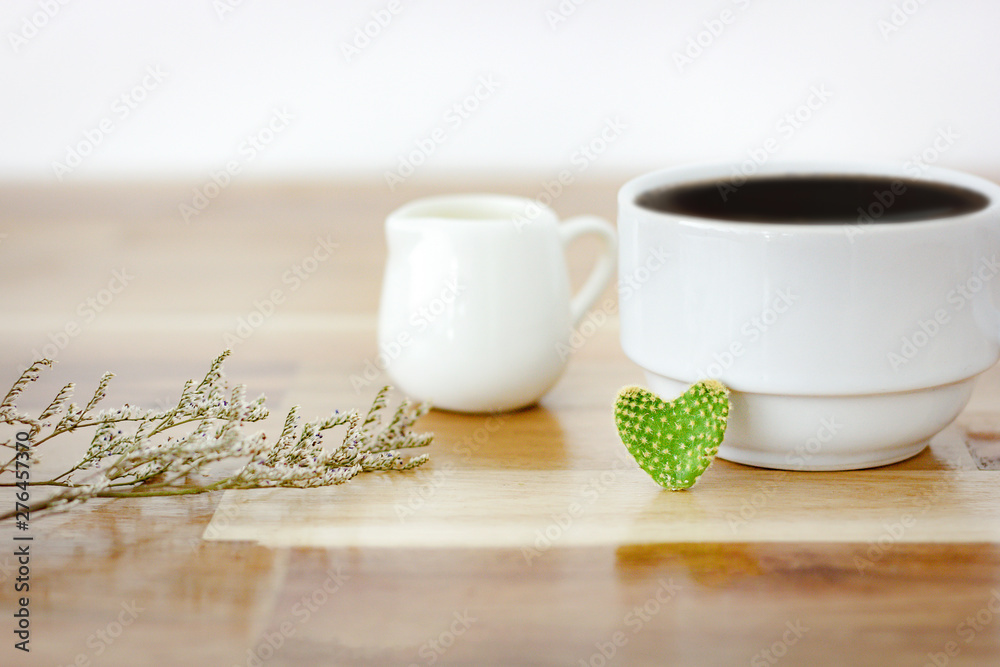 Closeup of cactus heart shape with black coffee in white cup and white cup of milk and dry leaf on wooden table. Selective and soft focus Closeup of cactus heart shape with black coffee in white cup and white cup of milk and dry leaf on wooden table. Selective and soft focus