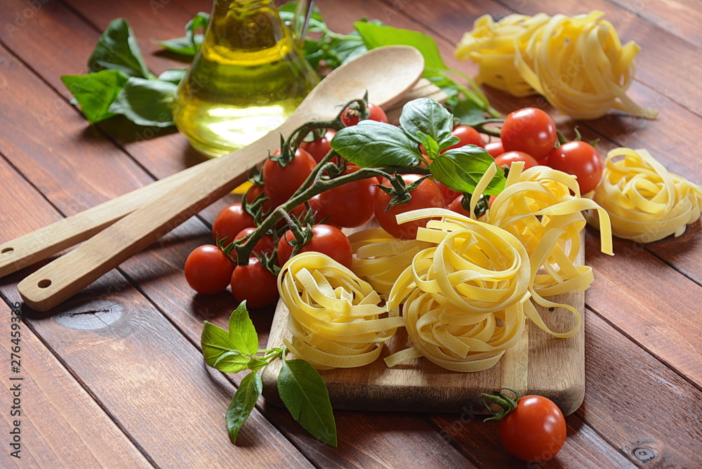 Concept of Italian food with raw pasta, tomato, basil and oil, selective focus Concept of Italian food with raw pasta, tomato, basil and oil, selective focus