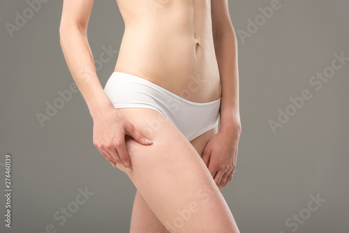 cropped view of young woman in white panties touching hip isolated on grey