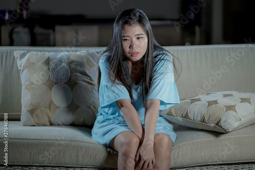 young beautiful sad and depressed Asian Chinese woman at home sofa couch feeling overwhelmed suffering anxiety crisis and depression problem crying