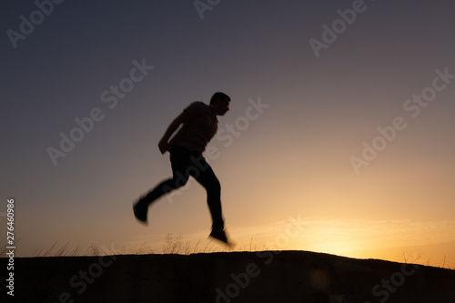 silhouette of man jumping at sunrise © robcartorres