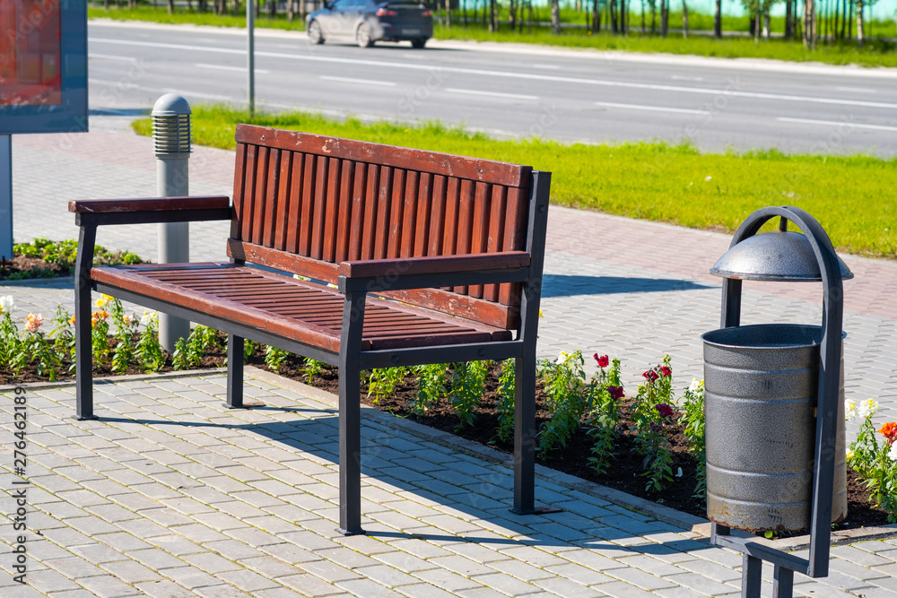 Wooden bench for rest and garbage bin in a city park. Wooden bench for rest and garbage bin in a city park.