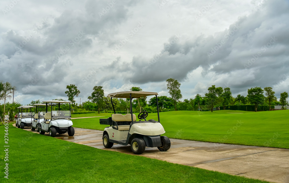 Golf carts parking near golf course with golfers and caddie are in competition,blue cloud sky background