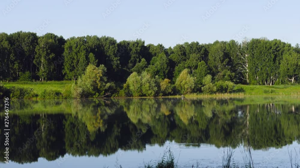 Fisherman on the boat in beautiful lake with the reflection of lush green forest Fisherman on the boat in beautiful lake with the reflection of lush green forest