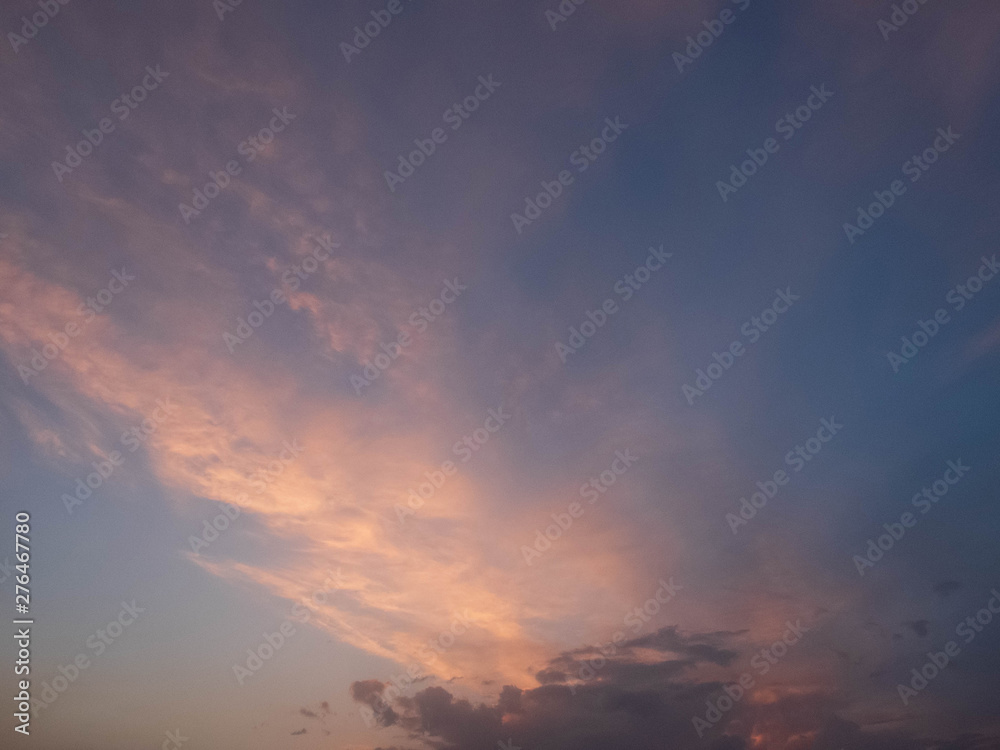 Bright multicolored clouds enlightened with rays of setting sun. Bright evening sky with pink, blue and purple cumulus, stratus and cirrus clouds