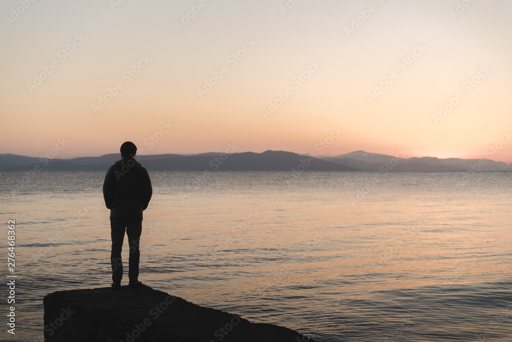 A man standing on a dock during sunrise on Kos, Greece. 