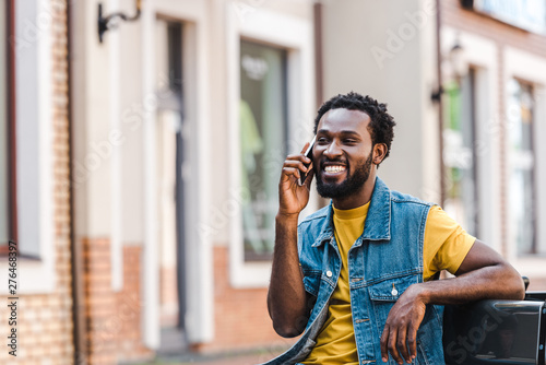 happy african american man smiling and talking on smartphone