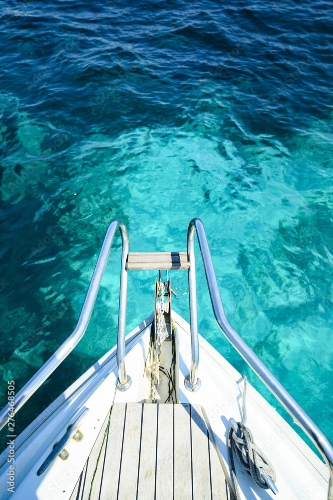 Obraz premium (Selective focus) Stunning view of a bow of a yacht sailing on a beautiful turquoise and transparent sea. (Emerald Coast) Sardinia, Italy.