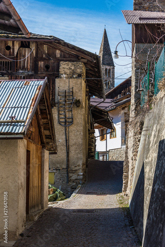 Fototapeta Naklejka Na Ścianę i Meble -  Bell tower of  Italian mountain chapel in Termenago - small village in Trentino, Italy. View from narrow alley.