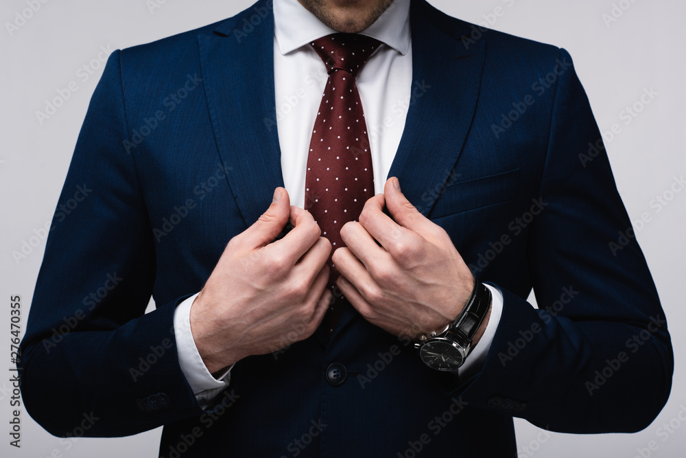 cropped view of confident businessman touching suit isolated on grey - obrazy, fototapety, plakaty 