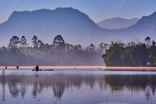 Lake surrounded by forest and mountain in a misty morning