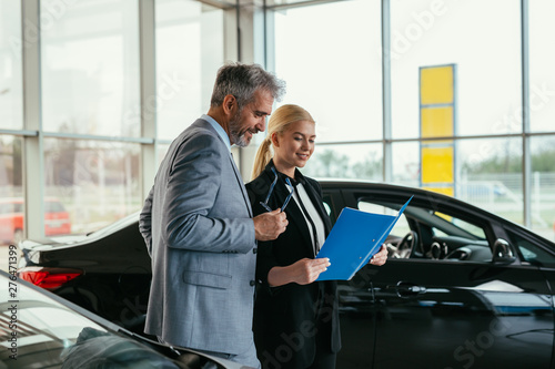 sales agent talking with customer in car dealership showroom