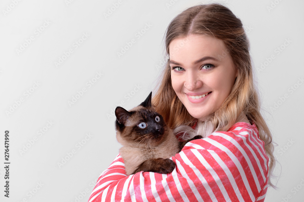 Obraz premium Young woman with cute Thai cat on light background