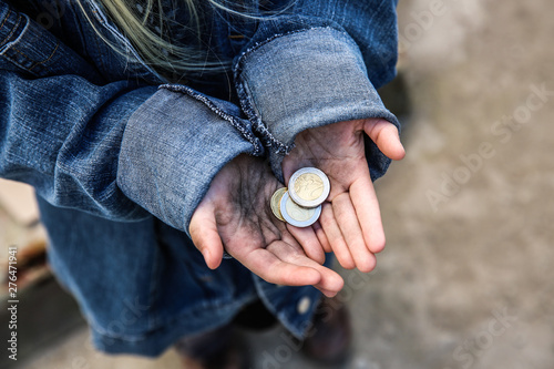 Homeless little girl with coins outdoors photo