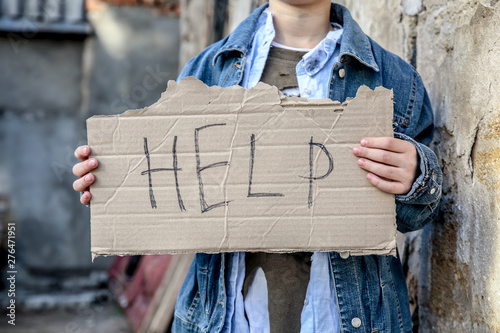 Homeless little boy begging for help outdoors photo