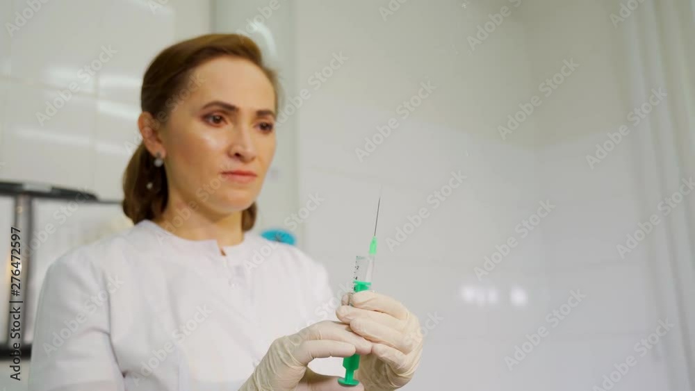 Hands of nurse holding syringe and sprinkle up the liquid medicine. Spraying drug from syringe. Squeezing liquid out of syringe