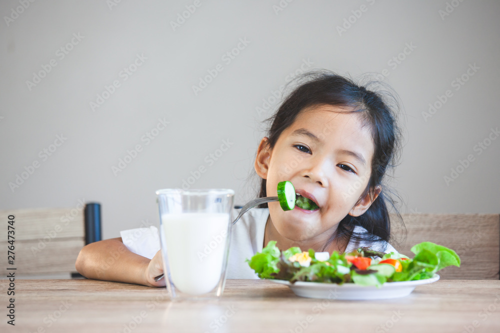 Cute asian child girl eating healthy vegetables and milk for her meal Cute asian child girl eating healthy vegetables and milk for her meal