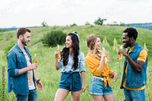 happy multicultural men and women holding bottles with beer