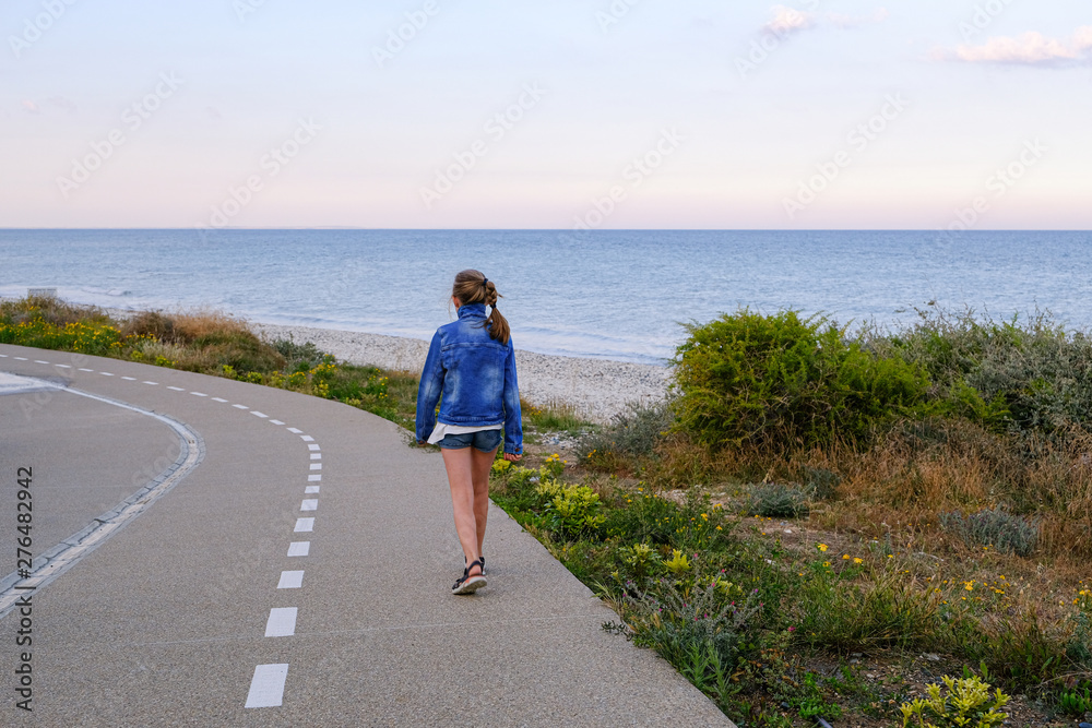 Teen girl on a walkway along the coast