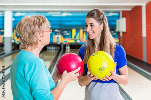 Mother and daughter holding bowling ball