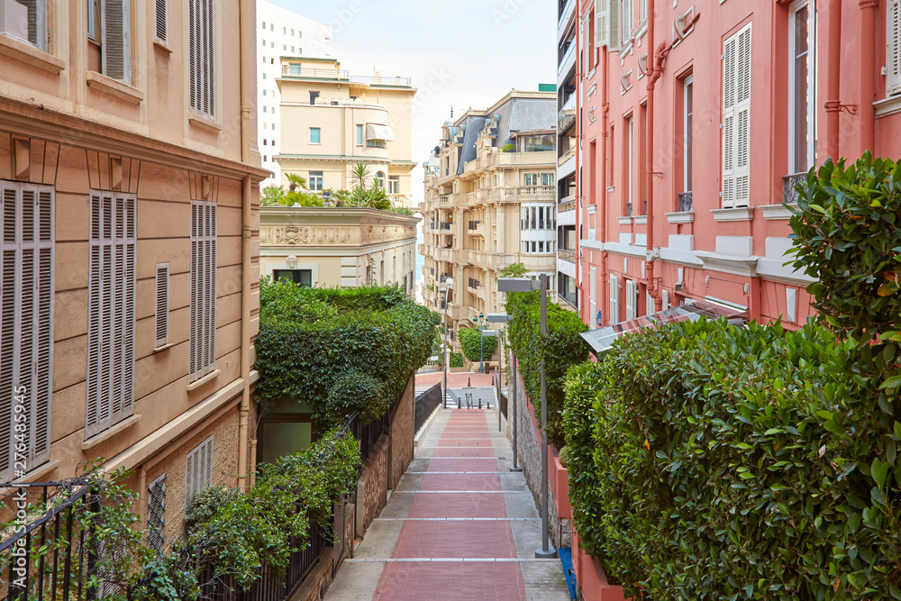 Narrow pedestrian alley in Monte Carlo with luxury buildings, summer day in Monaco