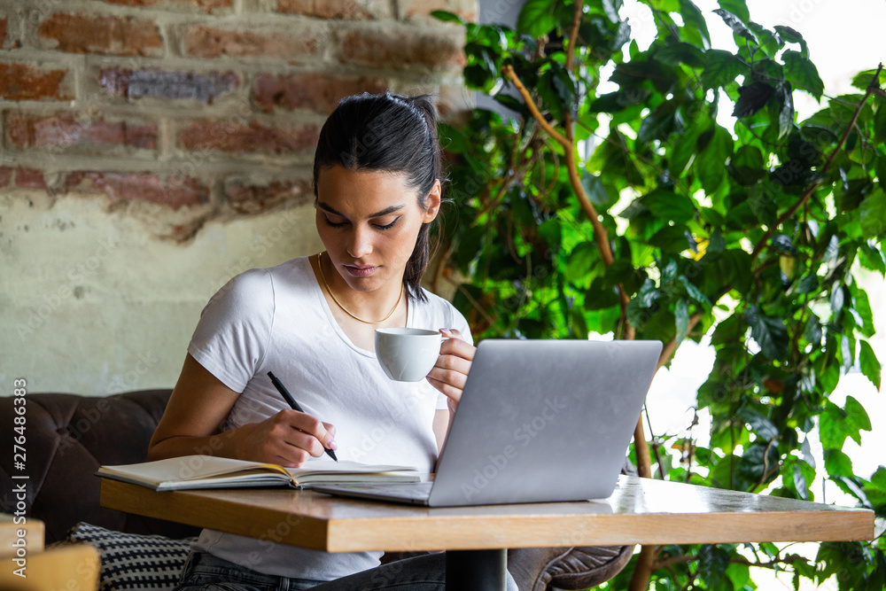 Young businesswoman is working in a cafeteria in her break.Woman taking a break. Enjoying work from coffee shop. Doing Business From coffee shop Young businesswoman is working in a cafeteria in her break.Woman taking a break. Enjoying work from coffee shop. Doing Business From coffee shop