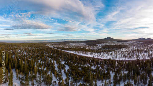 Aerial panorama of forests and mountains covered with snow on a winter day, Central Oregon, Bend near Mt Bachelor. Blue sky with dramatic white clouds. photo