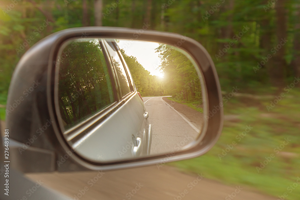Landscape in the sideview mirror of a car , on road countryside. The sun is shining