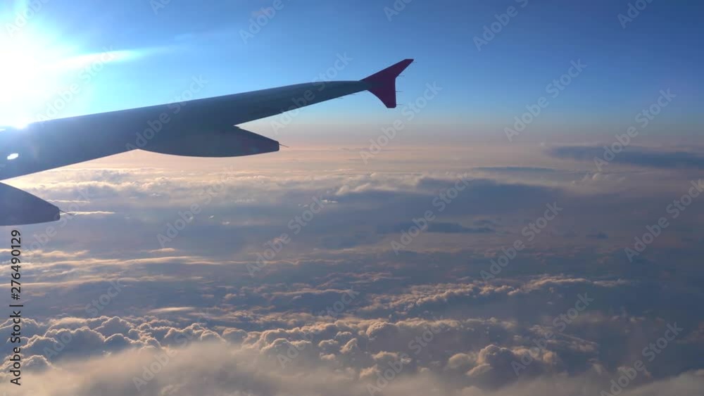 Up in the air, view of aircraft wing silhouette with dark blue sky horizon and cloud background in sun rise time, viewed from airplane window Up in the air, view of aircraft wing silhouette with dark blue sky horizon and cloud background in sun rise time, viewed from airplane window