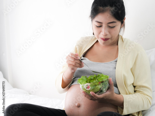 Asian pregnant woman eating fruit salad, lifestyle concept.